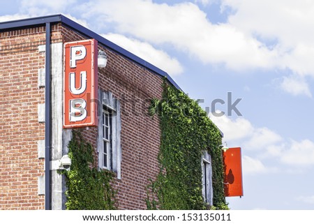 A pub sign located on the side of a brick building.