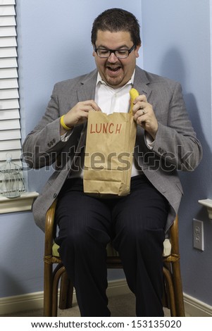A business man excited to be eating his paper sack lunch.