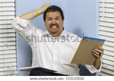 A business man angry with work gritting his teeth and pulling on his hair.