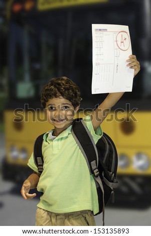 A child getting off the school bus showing a good grade on their homework.