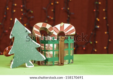 Craft items of candy canes and a Christmas tree around a plastic gift box.