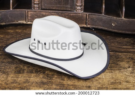 A white straw cowboy hat sitting on a wood table.