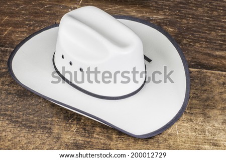 A white straw cowboy hat sitting on a wood table.