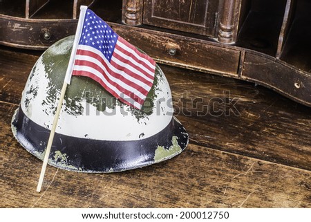 A soldier helmet and American flag sitting on a desk.