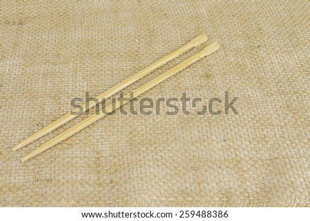Chop sticks sitting on a brown burlap background.