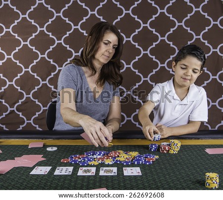 A mother and son sitting at a poker table learning how to play cards