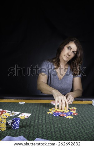 A woman sitting at a poker table playing cards with a black background