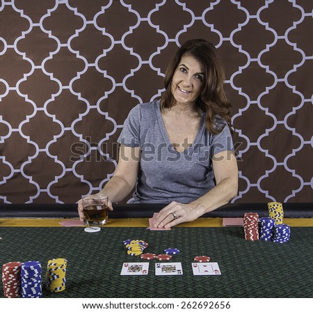 A woman sitting at a poker table playing cards with a brown background