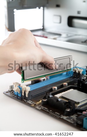 Assembling a high performance personal computer, Inserting DDR memory module into an DDR expansion socket, opened PC case in background, shallow depth of field, focus on hand