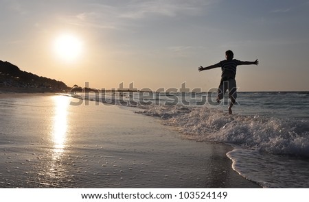 Happy man jumping over sea. Sand beach at sunset. Cuba vacation.