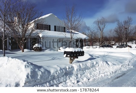 Single detached house on a sunny winter day. Snowed street after snow storm.