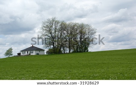 Farmland: green grass field and house on hill