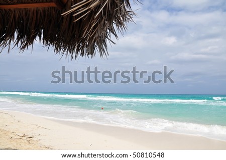 Cuba - Clear blue sea, pure white sand and sun shade made from palm-tree leaves.