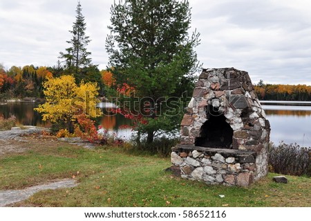 Outdoor stone fireplace located on the lake. Autumn, Ontario, Canada