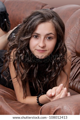 Pretty brunette woman\'s portrait with leather sofa in background