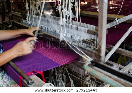 Unidentified old woman weaving  silk to sarong in traditional way at manual loom. THAILAND.