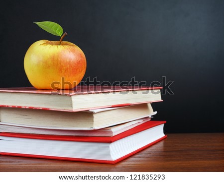 Back to school. Image of teacher\'s desk with a pile of textbooks and apple
