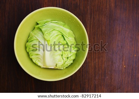 Image of white cabbage in a deep plate over wooden background