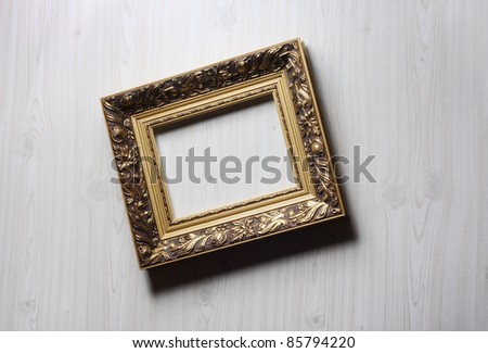 Image of lopsided golden art frame on the wall in dramatic light