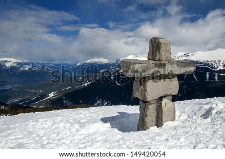 Stone sculpture Inukshuk stands prominently looking over the mountains and valleys atop Whistler Mountain, Canada