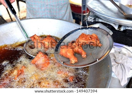 Breaded chicken deep frying in oil in a cast iron frying pan with local chef