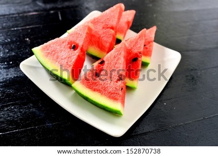 Slices of watermelon with black background on white dish
