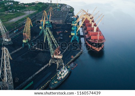 The Cargo Ship is in the Port Pier at the Loading of Coal at Sunset. Aerial View from Drone. Location Kandalaksha Town, Cola Peninsula, Russia