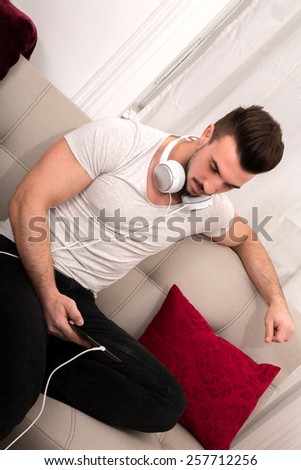 Man listening to music in the tablet while resting on the sofa