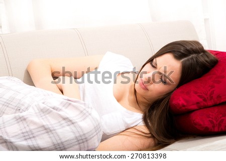 Young woman in the sofa with period pain