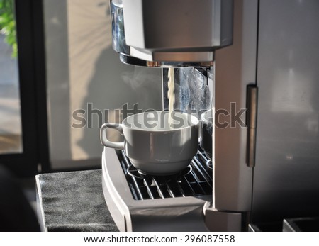 Fresh coffee drops falling to white cup, coffee machine preparing white cup of coffee
