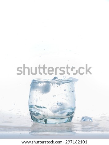cold water splash on a glass on white background, Ice cubes splashing into glass of water