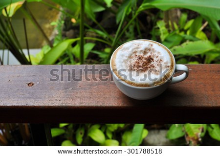 white cup of hot coffee on natural green background