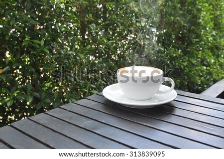 white cup of hot coffee on wooden table in coffee shop,white cup of hot coffee on wooden table on green natural background