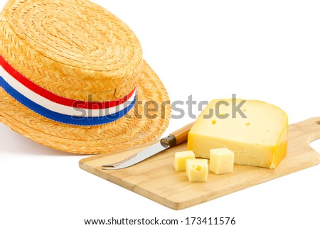 piece of cheese on cutting board with cheese knife and orange hat