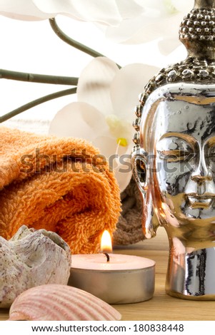 buddha figure with orange towel, candle, shells and silk orchid isolated