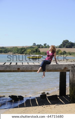 Pretty young woman sunbathing on landing stage in brittany, france