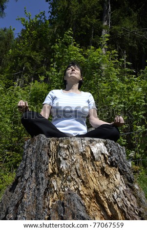 Senior woman practicing yoga in the forest.