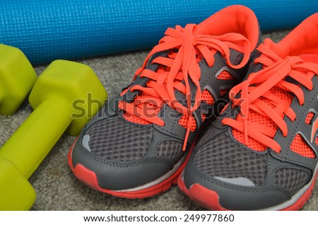 Bright sport shoes with dumbbell and yoga mat