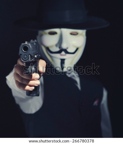 Person in anonynomous mask with gun in hand