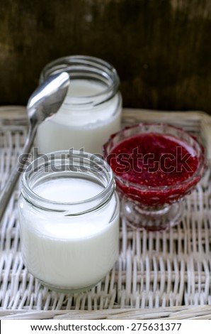 Two jars of yogurt and raspberry jam in a vase