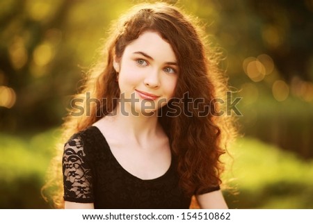 Beautiful girl thinking. Beauty portrait of a gorgeous young woman with fabulous hair, smiling & looking to left. Processed from RAW, detailed retouching.