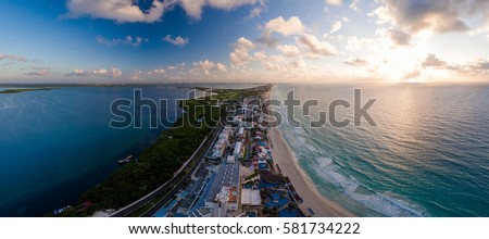 Aerial panorama of Hotel Row in Cancun, Mexico featuring the major hotels and resorts with white sandy beaches and blue ocean during a morning sunrise