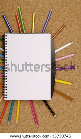 color pencils with note pad on wooden background