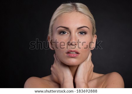 Beautiful blonde hair women isolated on black background looking at camera with hands and neck, arms. Close up. Studio shot.