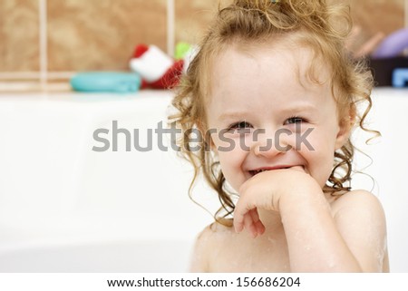 Funny cheerful toddler cleaning teeth in the bath