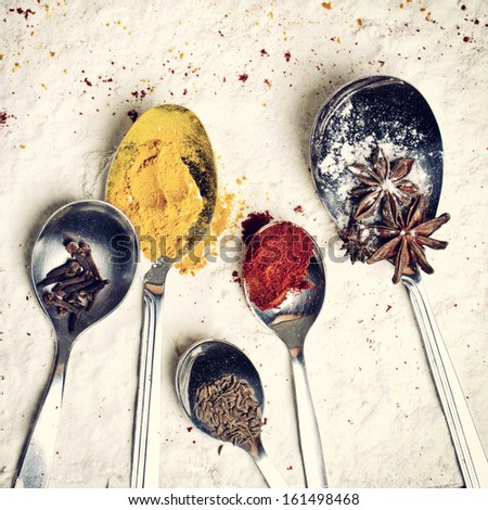 Spoons with spices lying on the flour background