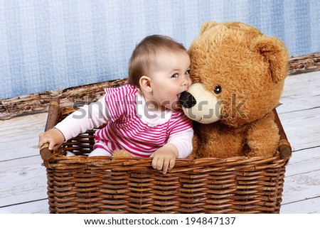 Little child with teddy bear sitting in the basket