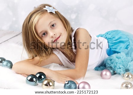 Beautiful little girl wearing tutu skirt lying on the floor with christmas balls