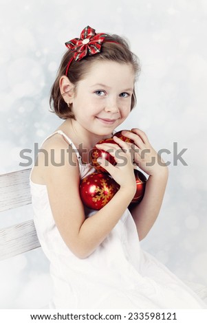 Cute girl with freckles on her nose holding christmas balls