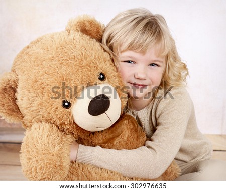 Little girl cuddling with her big plush teddy bear